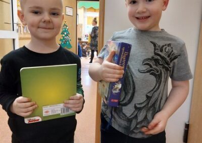 Chłopcy z uśmiechem prezentują wylosowane książeczki.