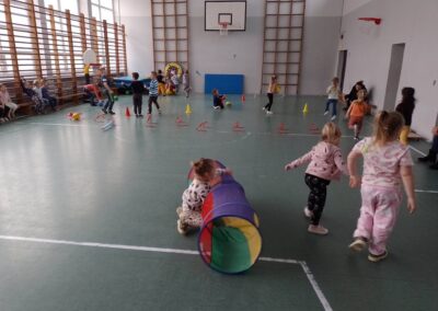 Dzieci uczestniczą w zajęciach sportowych na sali gimnastycznej.