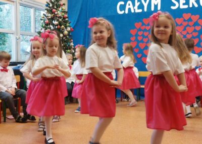 Dziewczynki w różowych spódniczkach tańczą twista.