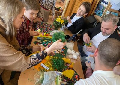 Dzieci wraz z rodzicami pracują przy tworzeniu ozdób.