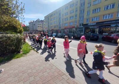 Dzieci z flagami maszerują ulicami miasta.
