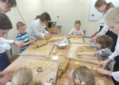 Dzieci z zaangażowaniem wycinają ciasteczka.