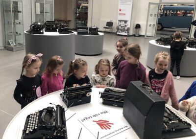 Dziewczynki oglądają stare maszyny do pisania.
