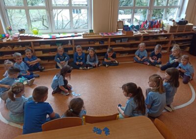 Dzieci układają serce z niebieskich puzzli.