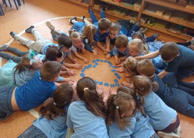 Dzieci układają serce z niebieskich puzzli.