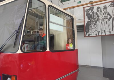 Dzieci siedzą w symulatorze jazdy tramwajem.