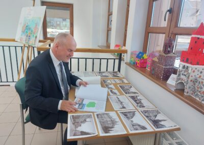 Burmistrz wpisuje się do pamiątkowej księgi wystawy.