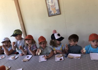 Dzieci z grupy Jeżyków jedzą kiełbaski przy stole.