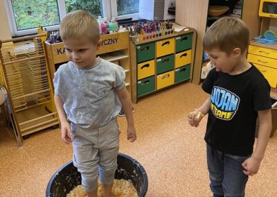 Dzieci ubijają stopami kapustę w misce.