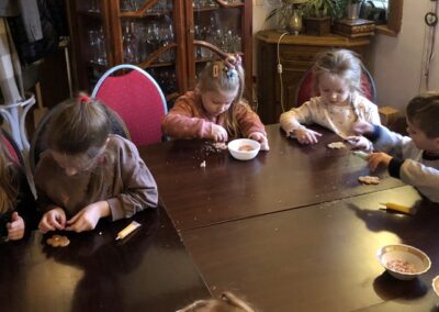 Dzieci dekorują pierniki przy stole.