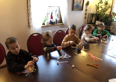 Dzieci tworzą bożonarodzeniowy łańcuch z kolorowego papieru.