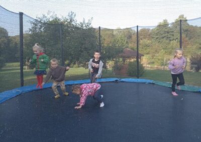 Dzieci skaczą i robią fikołki na trampolinie.