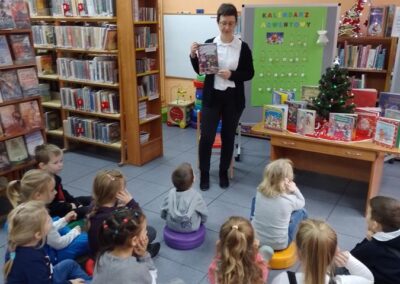 Pani z biblioteki przedstawia dzieciom książkę ze świątecznym opowiadaniem.