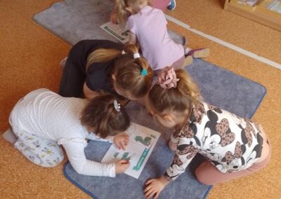 Dzieci składają obrazek dinozaura z części.