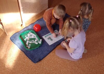 Dzieci składają obrazki dinozaurów.