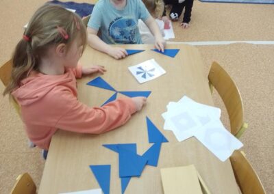 Dzieci składają wzory z niebieskich trójkątów.
