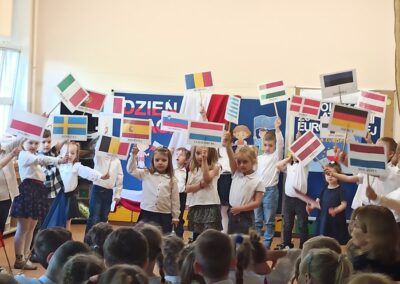 Dzieci śpiewają piosenkę, machając flagami.